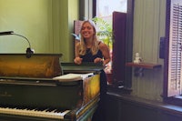 a woman smiling in front of a green piano